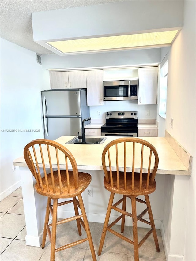 kitchen featuring appliances with stainless steel finishes, a kitchen bar, kitchen peninsula, and sink