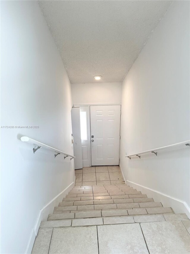 stairway featuring tile patterned floors and a textured ceiling