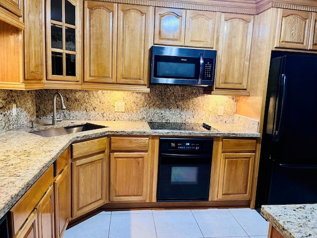 kitchen with light stone countertops, sink, decorative backsplash, light tile patterned floors, and black appliances