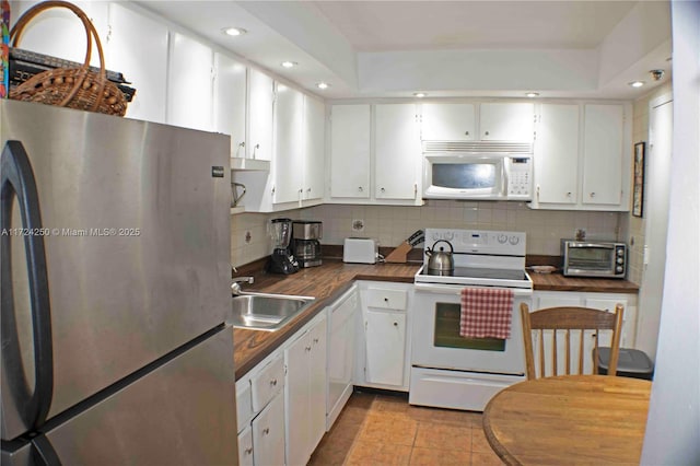 kitchen with sink, light tile patterned floors, white appliances, decorative backsplash, and white cabinets