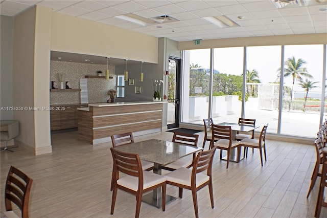 dining space with light hardwood / wood-style flooring and a paneled ceiling