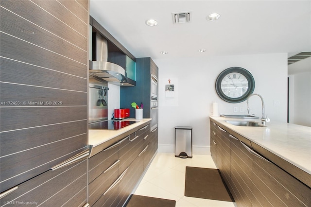 kitchen with light tile patterned floors, sink, appliances with stainless steel finishes, and wall chimney exhaust hood