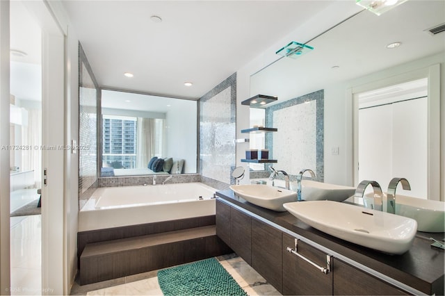 bathroom featuring a relaxing tiled tub and vanity