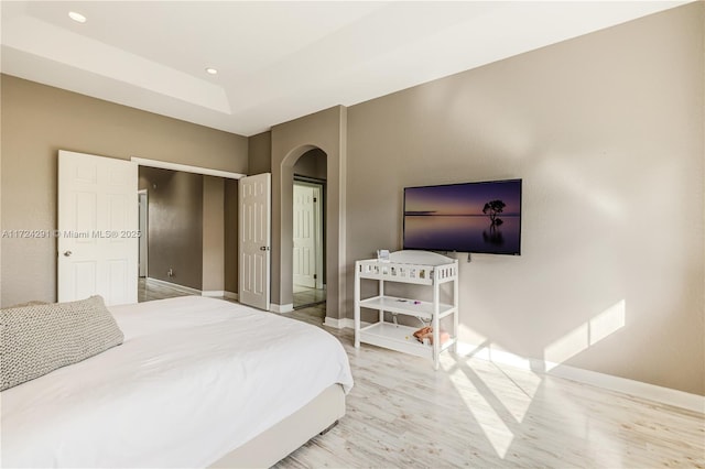 bedroom featuring a raised ceiling and light hardwood / wood-style floors