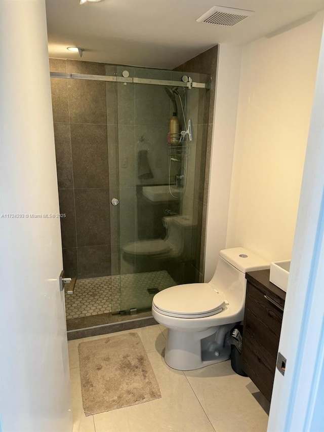 bathroom with tile patterned floors, vanity, toilet, and a shower with shower door