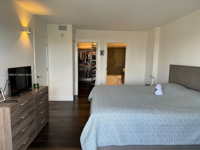 bedroom featuring a walk in closet, ensuite bathroom, a closet, and dark hardwood / wood-style flooring