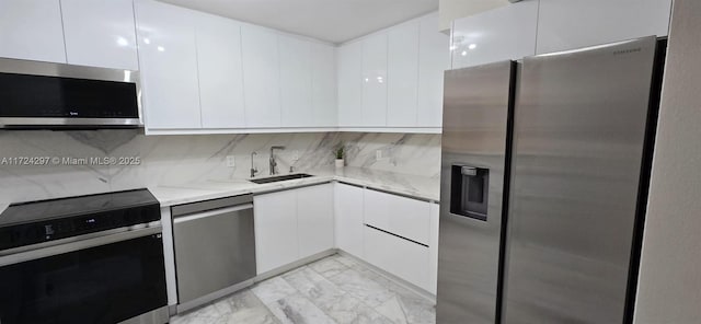 kitchen featuring light stone countertops, sink, stainless steel appliances, tasteful backsplash, and white cabinets