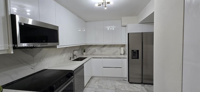 kitchen featuring backsplash, sink, light stone countertops, appliances with stainless steel finishes, and white cabinetry