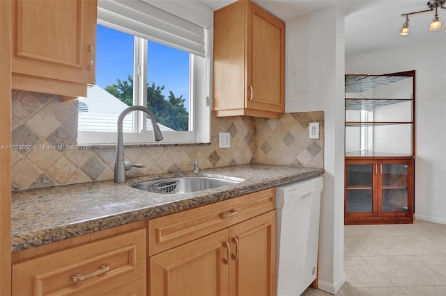 kitchen with light tile patterned floors, white dishwasher, light brown cabinets, a sink, and tasteful backsplash