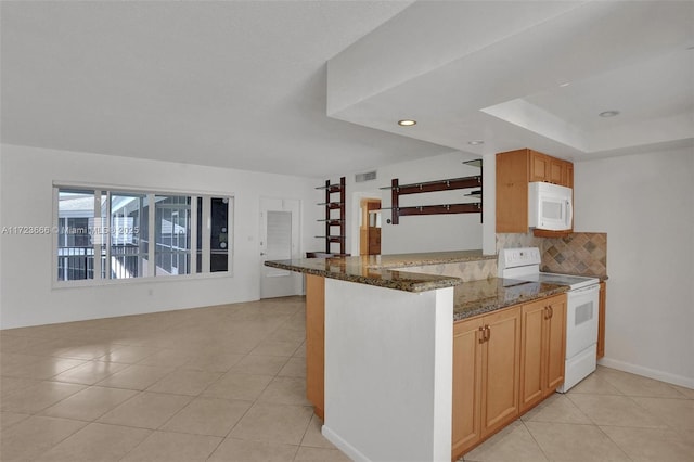 kitchen with light tile patterned floors, decorative backsplash, dark stone counters, white appliances, and a peninsula