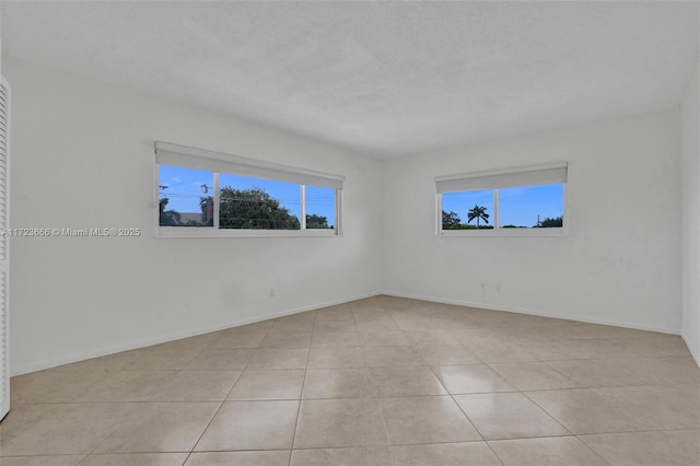 unfurnished room featuring baseboards and light tile patterned flooring