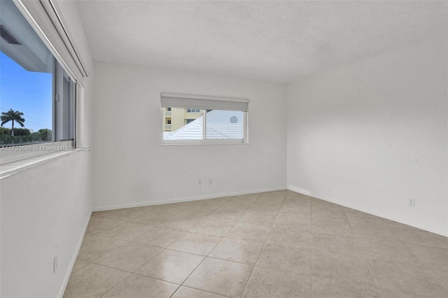 spare room with a wealth of natural light, visible vents, and baseboards