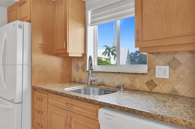 kitchen featuring white appliances, light stone counters, decorative backsplash, and a sink