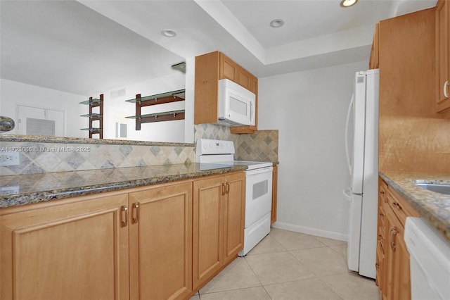 kitchen with light tile patterned floors, decorative backsplash, dark stone counters, white appliances, and baseboards