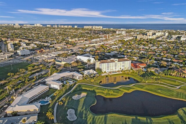 drone / aerial view with a water view, view of golf course, and a view of city