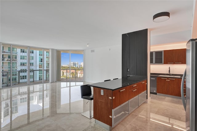 kitchen featuring a center island, sink, stainless steel appliances, expansive windows, and a kitchen bar