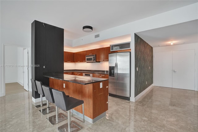 kitchen featuring a kitchen breakfast bar, kitchen peninsula, tasteful backsplash, and appliances with stainless steel finishes