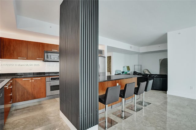 kitchen with a kitchen bar, backsplash, and appliances with stainless steel finishes