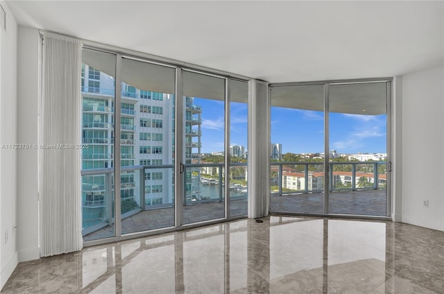 spare room with a water view, plenty of natural light, and expansive windows