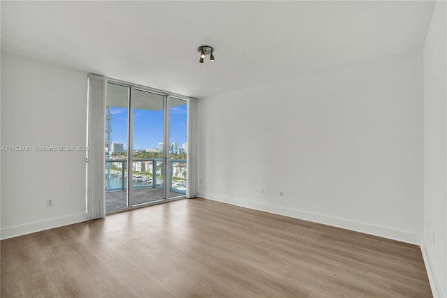 unfurnished room with light hardwood / wood-style floors and a wall of windows