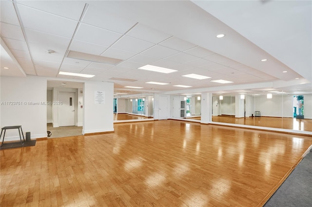 exercise room with a drop ceiling and wood-type flooring