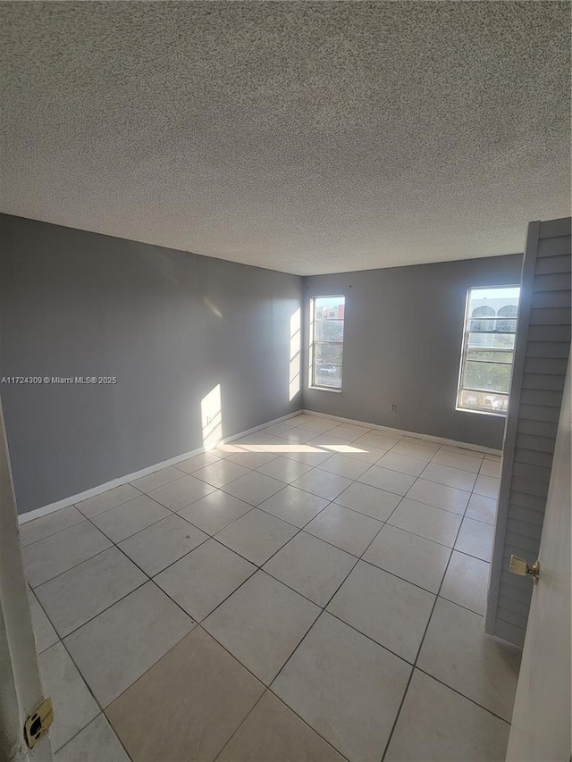 spare room with light tile patterned flooring and a textured ceiling