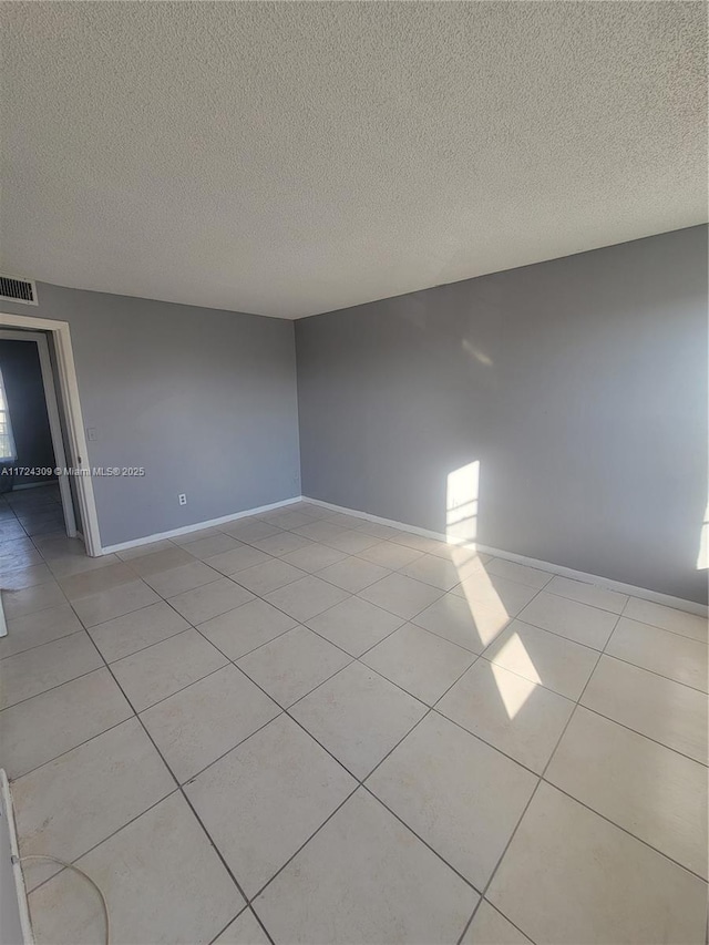 tiled empty room with a textured ceiling