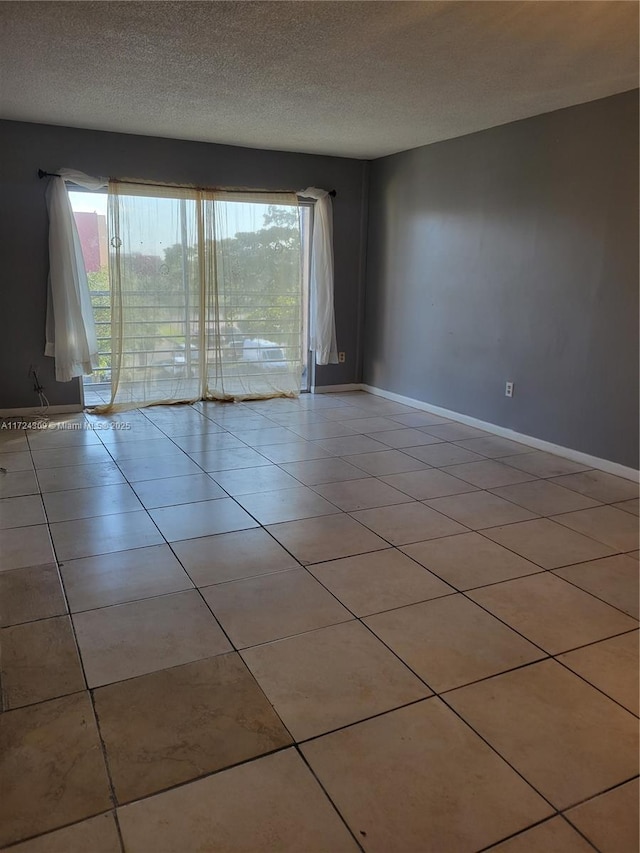 tiled empty room with a textured ceiling