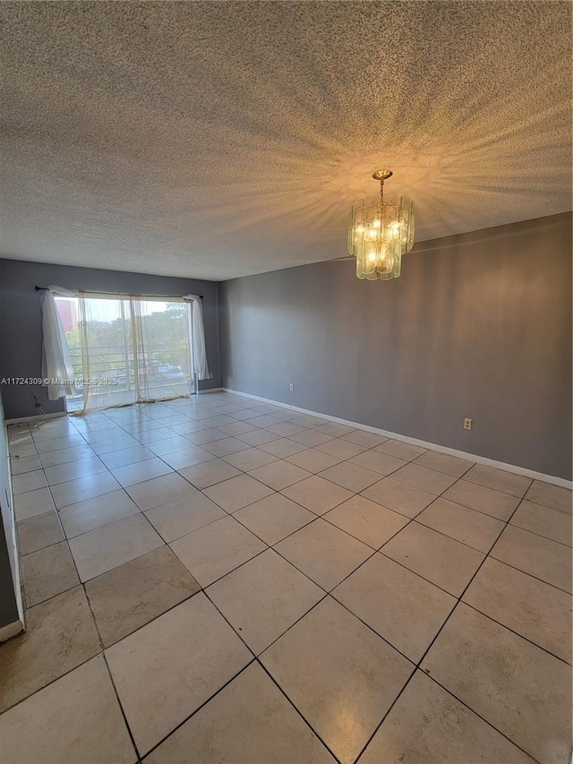 tiled empty room featuring a textured ceiling and a chandelier