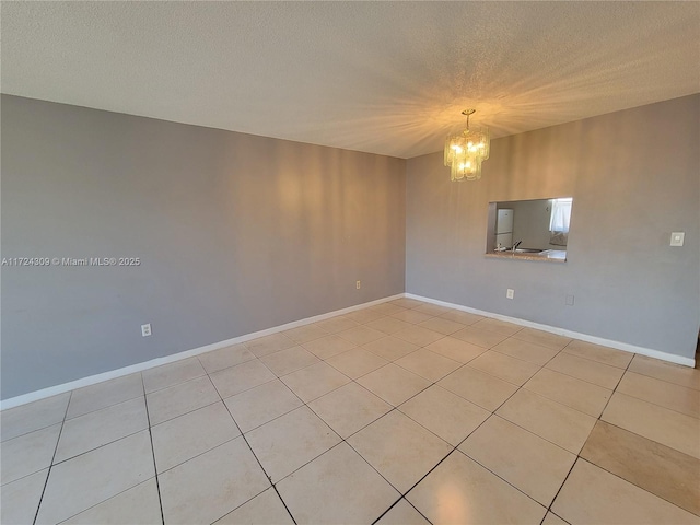 tiled spare room with a textured ceiling and a notable chandelier