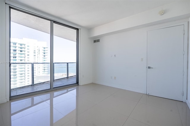 tiled empty room featuring floor to ceiling windows