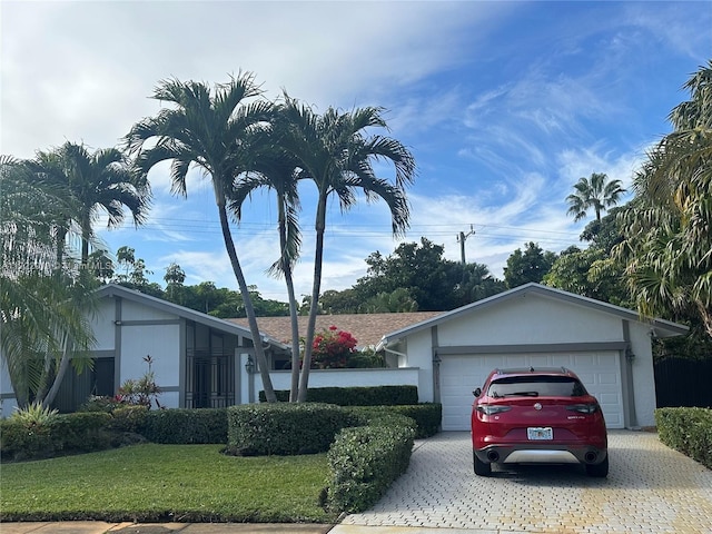 ranch-style home with a garage and a front lawn