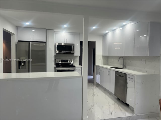 kitchen featuring decorative backsplash, white cabinetry, sink, and appliances with stainless steel finishes