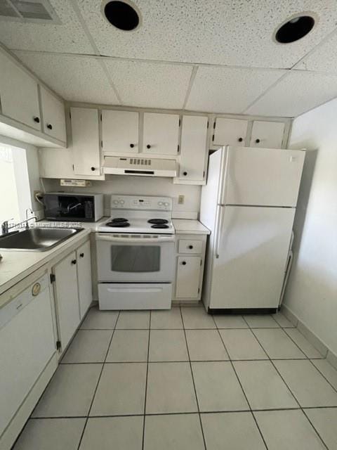 kitchen featuring white appliances, a paneled ceiling, light tile patterned floors, sink, and white cabinetry