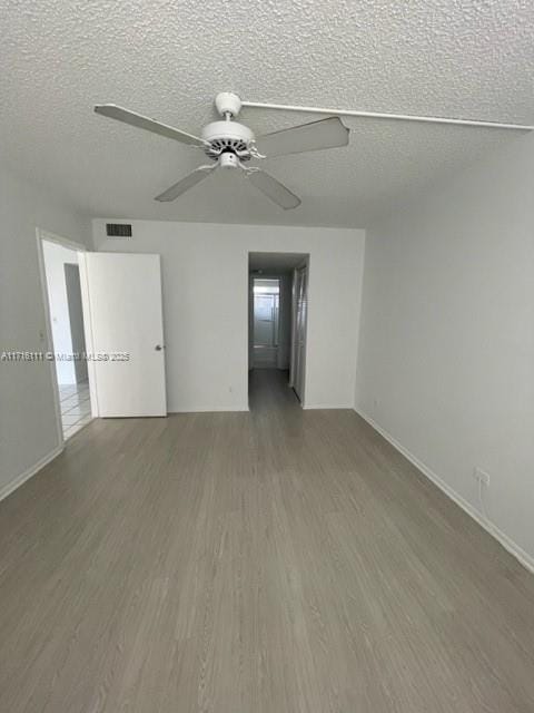 spare room with a textured ceiling, ceiling fan, and dark wood-type flooring