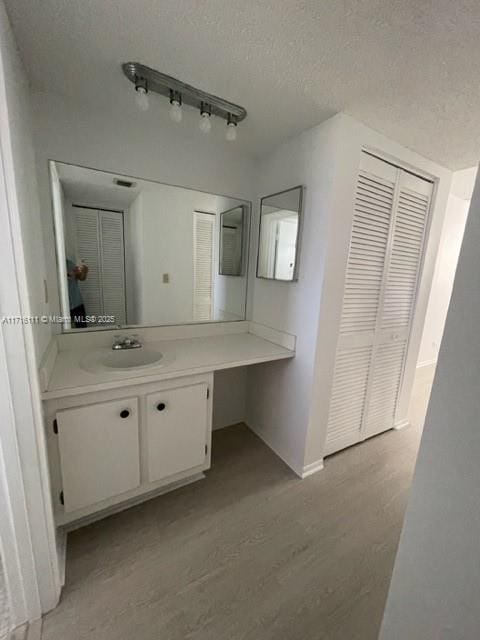 bathroom featuring hardwood / wood-style flooring, a textured ceiling, track lighting, and vanity