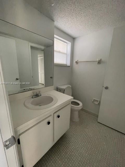 bathroom featuring toilet, vanity, and a textured ceiling