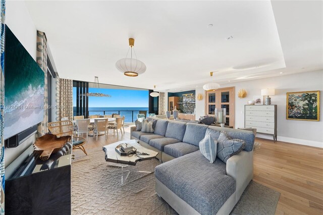 living room featuring a water view, expansive windows, and light wood-type flooring