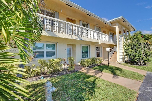 view of front of home with a balcony and a front lawn