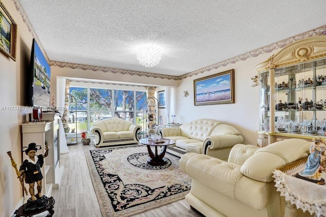 living room with a textured ceiling, a chandelier, and light hardwood / wood-style flooring