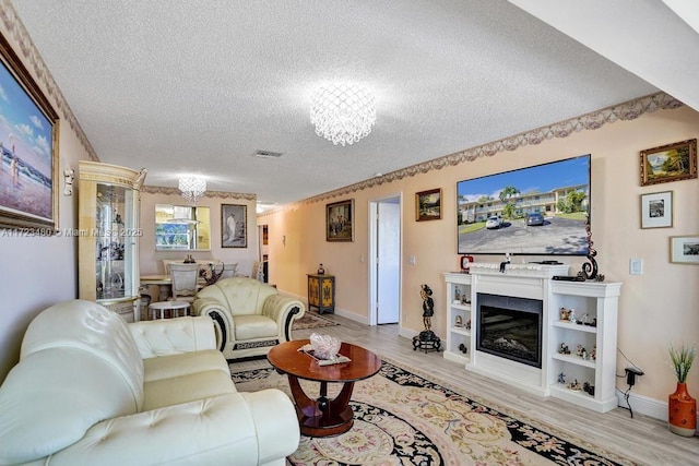 living room featuring a textured ceiling, a chandelier, and light wood-type flooring