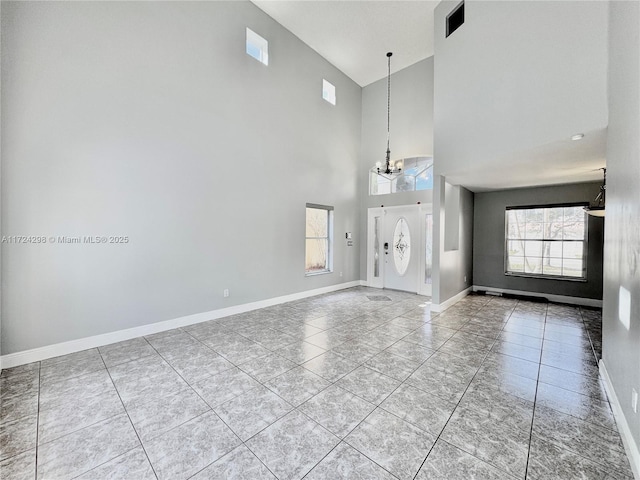 foyer with light tile patterned floors, a towering ceiling, and a notable chandelier