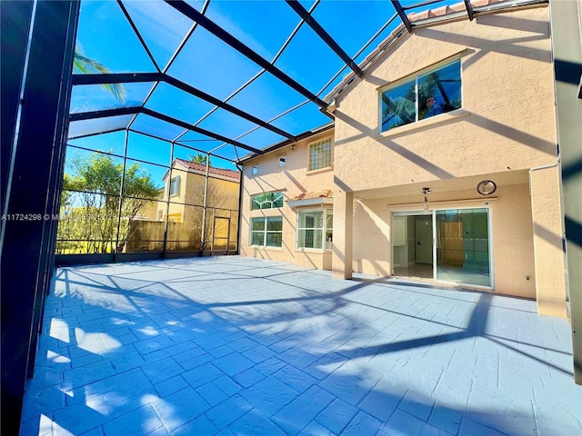 rear view of property featuring glass enclosure and a patio