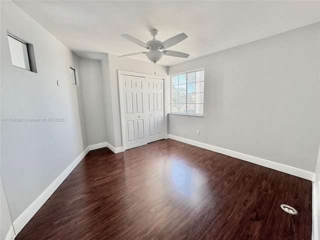 unfurnished bedroom featuring ceiling fan, a closet, and dark wood-type flooring