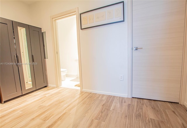 unfurnished bedroom with light wood-type flooring and ensuite bathroom