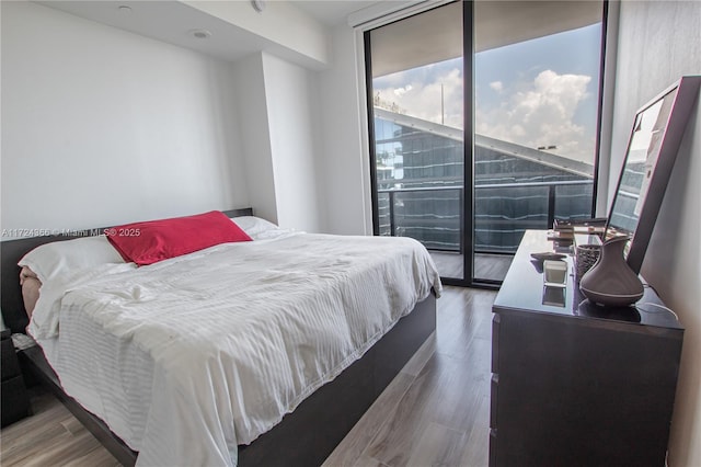 bedroom featuring access to outside, floor to ceiling windows, and hardwood / wood-style flooring