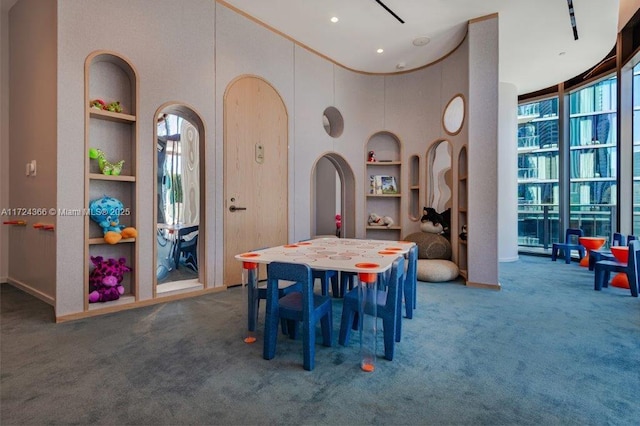 dining area with dark colored carpet, a towering ceiling, and built in features