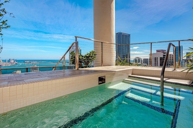 view of swimming pool with a water view and a hot tub