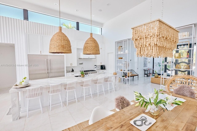 tiled dining area with a chandelier and a high ceiling