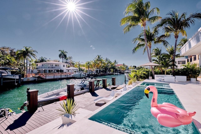 view of swimming pool with a dock, a water view, and a patio